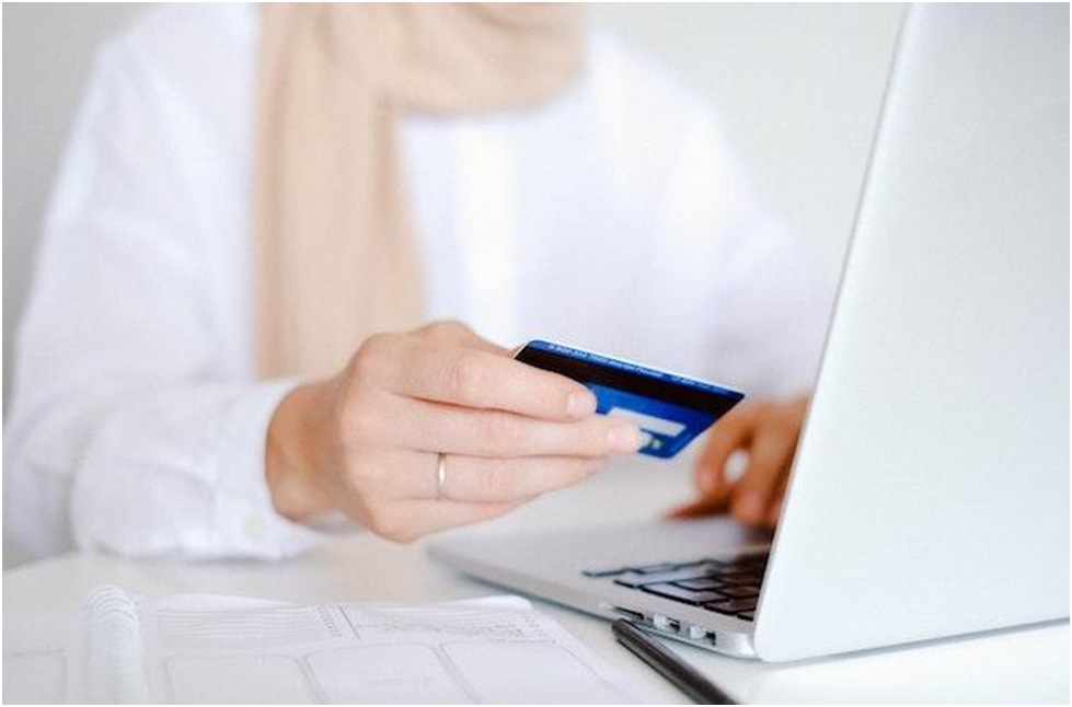  a tenant taking advantage of a convenient online rent payment system holds a blue credit card and enters payment information onto their laptop